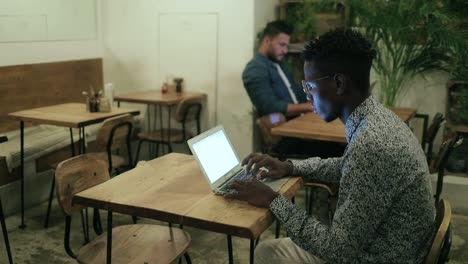 Joven-Independiente-Afroamericano-Usando-Una-Computadora-Portátil-En-Una-Cafetería